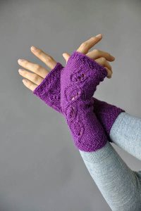 Free Knitting Pattern for Flight of Fancy Mitts. These delicate mitts are knit in the round from the cuff upward. Twist-stitch leaves on a background of reverse stockinette stitch are mirrored on right and left hands.