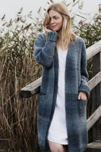 This long ladies cardigan with pockets is knitted in a combination of mock fisherman's rib and broken seed stitch.