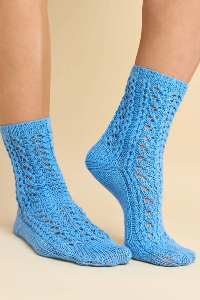 A pair of knitted socks featuring an elegant lace motif with twisted stitches and centered double decreases, worked in a bright teal yarn.